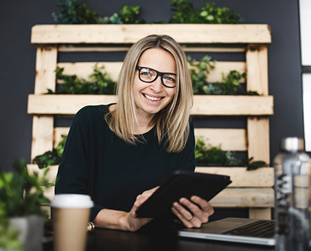 blonde Dame mit Brille mit Tablet in Händen 