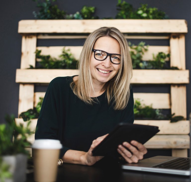 blonde Dame mit Brille mit Tablet in Händen